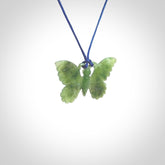Small Butterfly design pendant carved in nephrite jade. Real jade jewellery for sale online with NZ Pacific. Small butterfly pendant hand made in Jade, provided with pacific blue cord and packaged in a woven kete pouch.